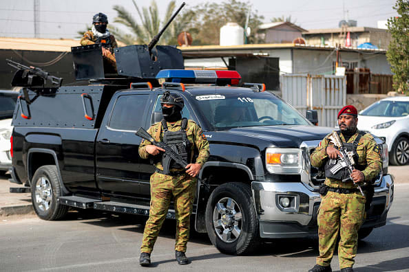 Iraqi security forces stand guard during a funerary procession for a slain member of Iraq
