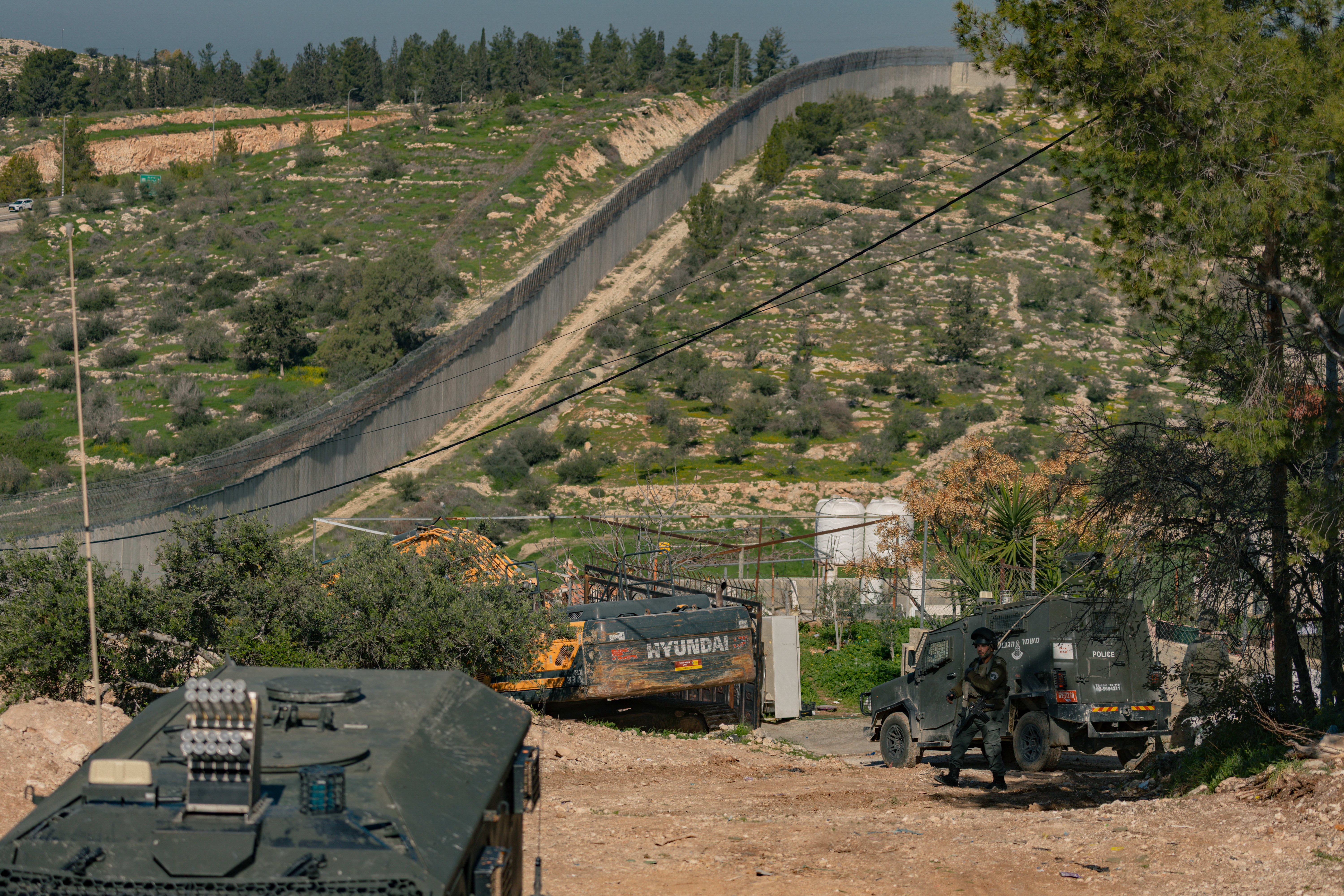 Israeli military vehicles move along a road next to a concrete barrier close to the village of Beit Awwa near Hebron in the West Bank (photo credit: Photo by Mosab Shawer / Middle East Images / AFP via Getty Images)