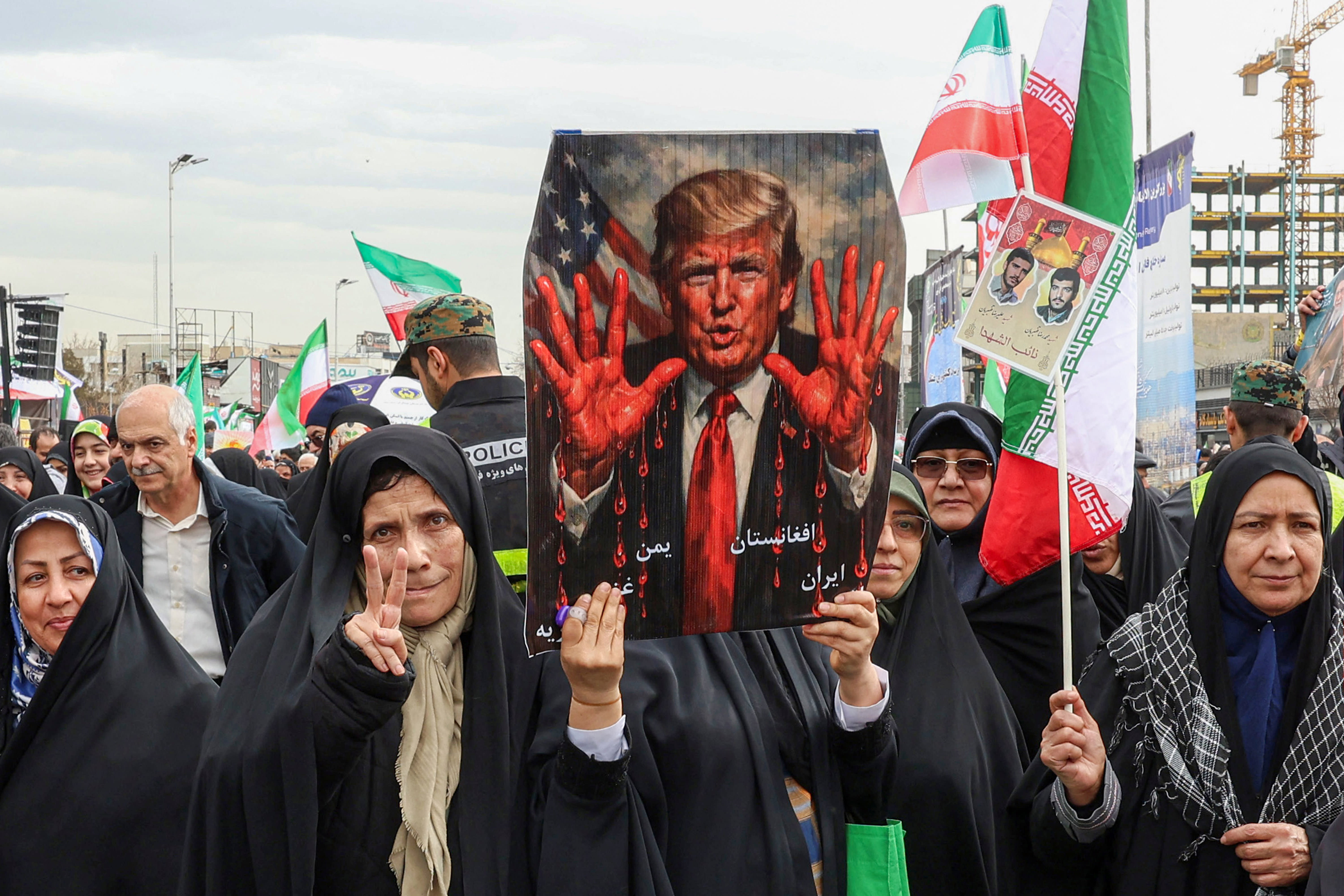 Women march with a sign depicting US President Donald Trump with bloodied hands in Tehran on February 11, 2026, during a rally marking the 47th anniversary of the 1979 Islamic revolution. (photo credit: AFP VIA GETTY IMAGES)