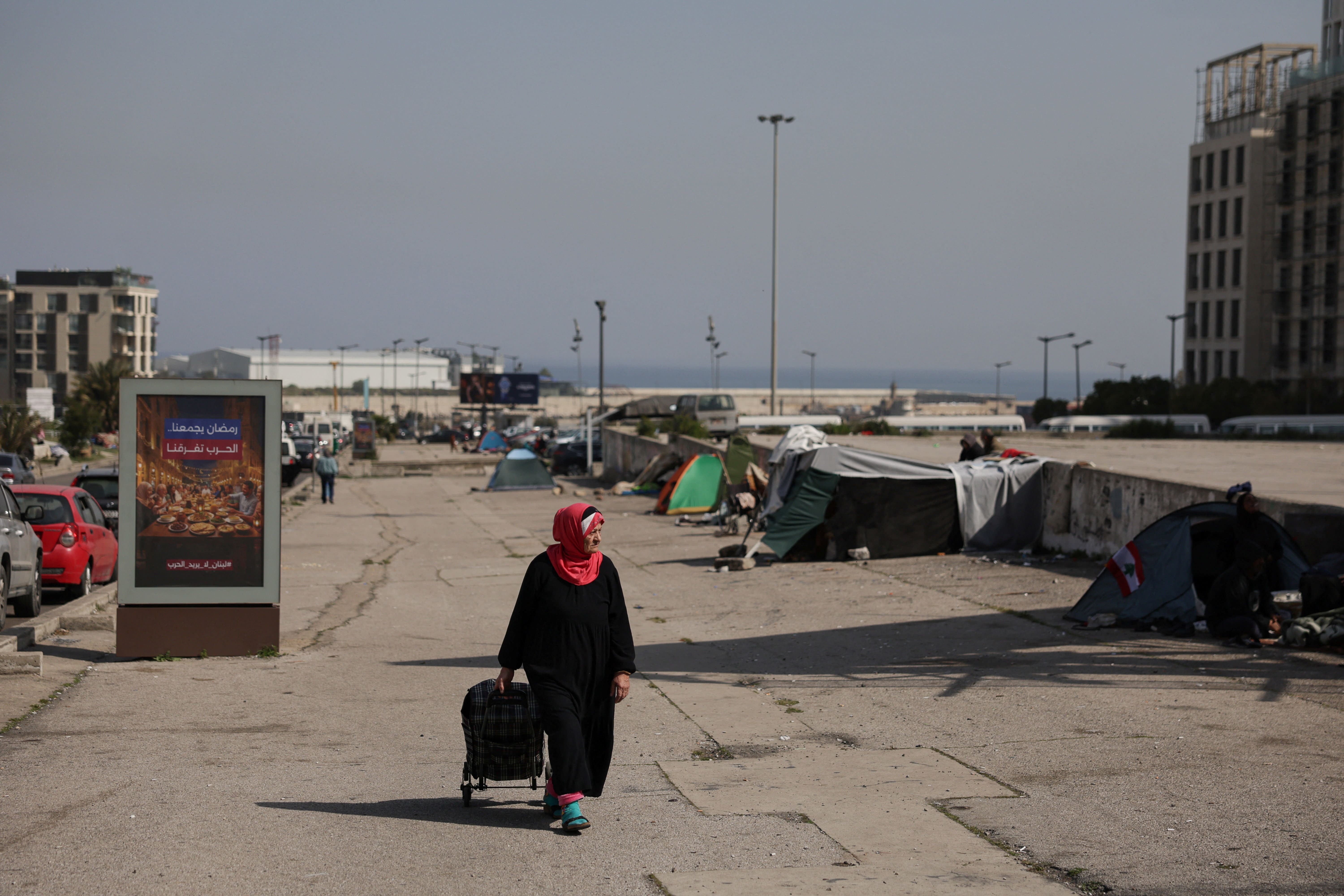 A woman walks near tents set up by displaced people, following an escalation between Hezbollah and Israel amid the US-Israeli conflict with Iran, in Beirut, Lebanon, March 13, 2026. (photo credit: REUTERS/KHALIL ASHAWI)