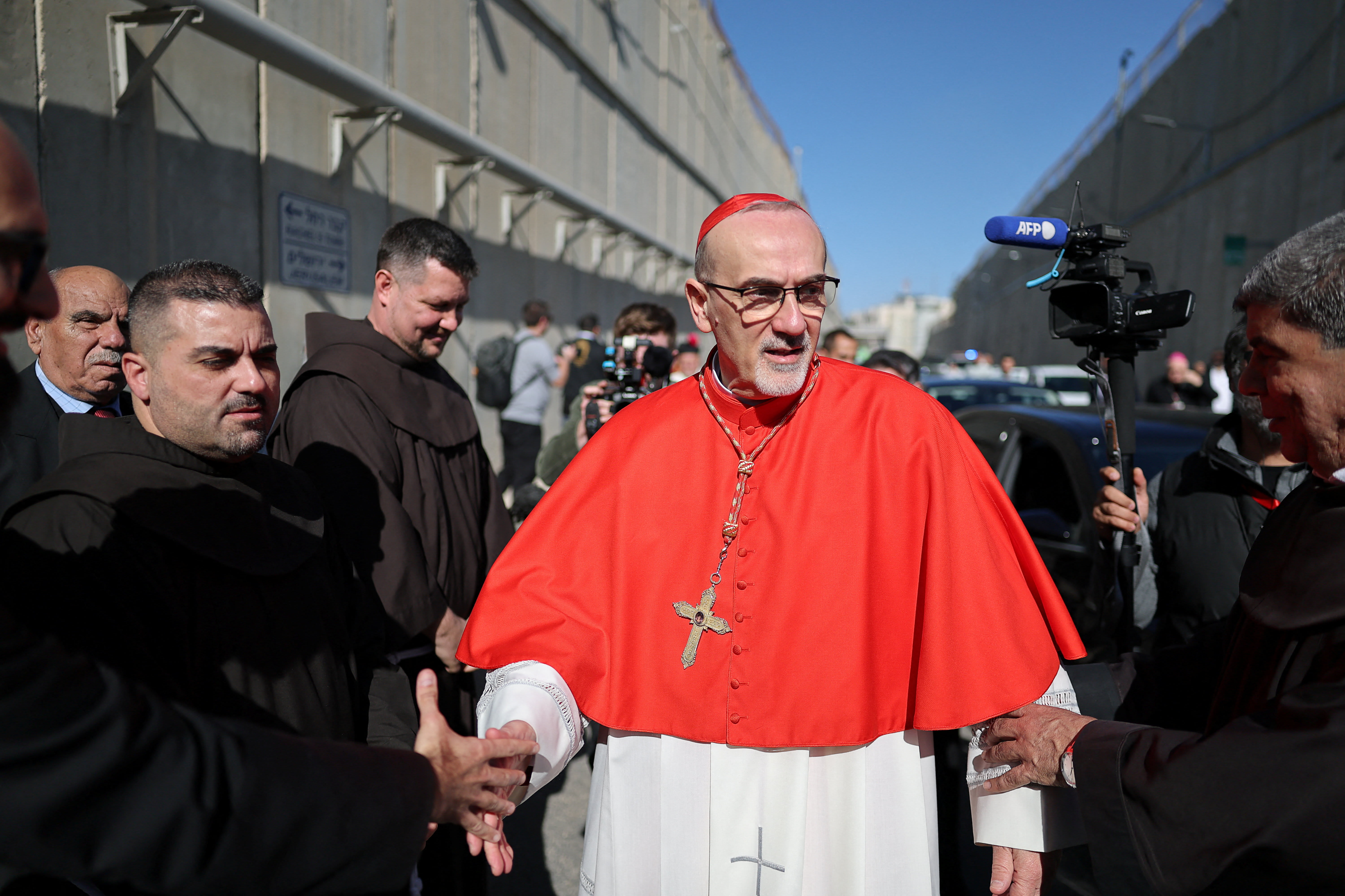 LATIN PATRIARCH of Jerusalem, Cardinal Pierbattista Pizzaballa, shakes hands with a person, as he passes through an Israeli checkpoint to attend Christmas celebrations in Bethlehem, in the West Bank, on Christmas Eve, December 24, 2025. (photo credit: REUTERS/AMMAR AWAD)
