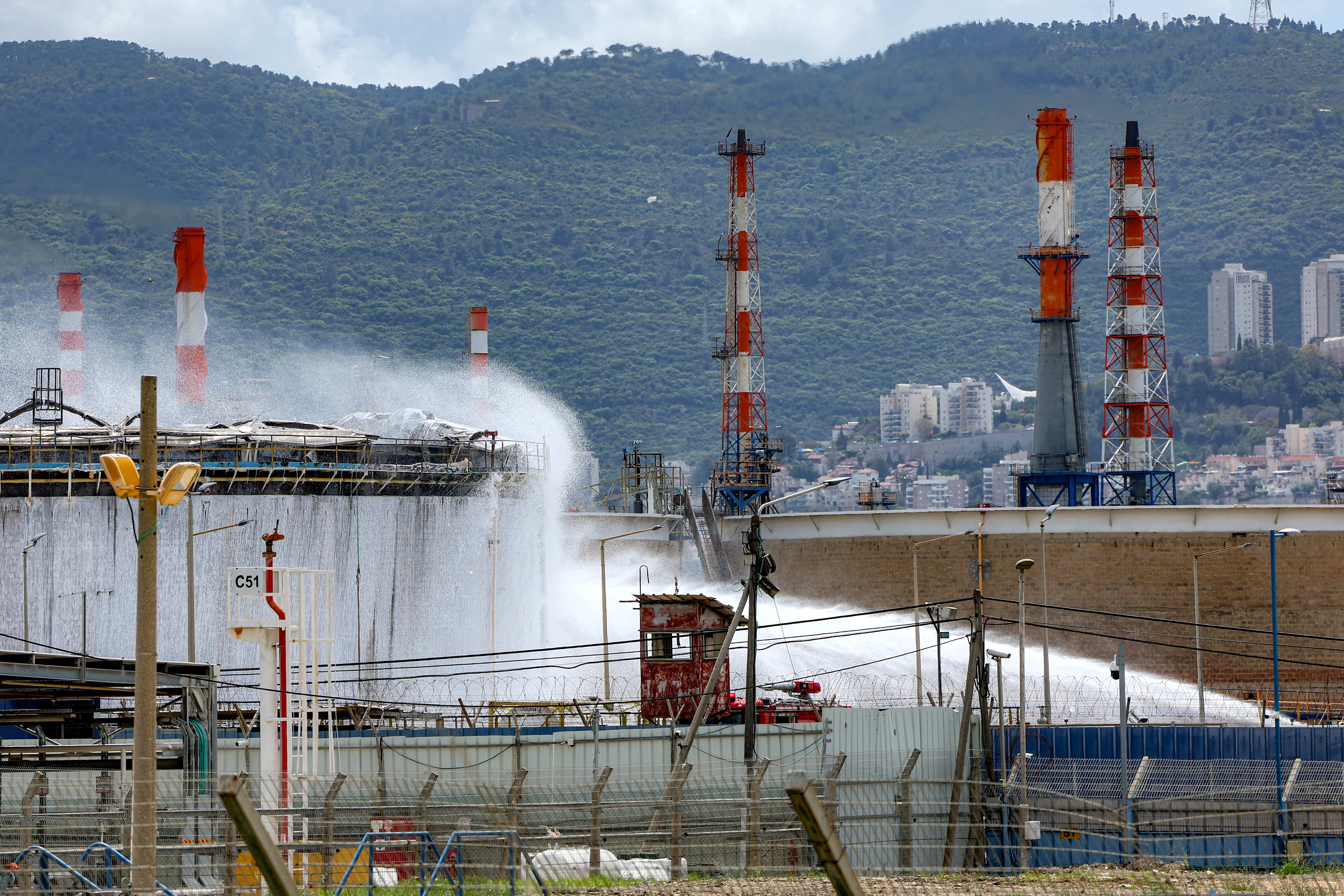 Firefighters attempt to extinguish a fire following a projectile impact on a refinery on Haifa on March 30.  (photo credit: JACK GUEZ/AFP VIA GETTY IMAGES)