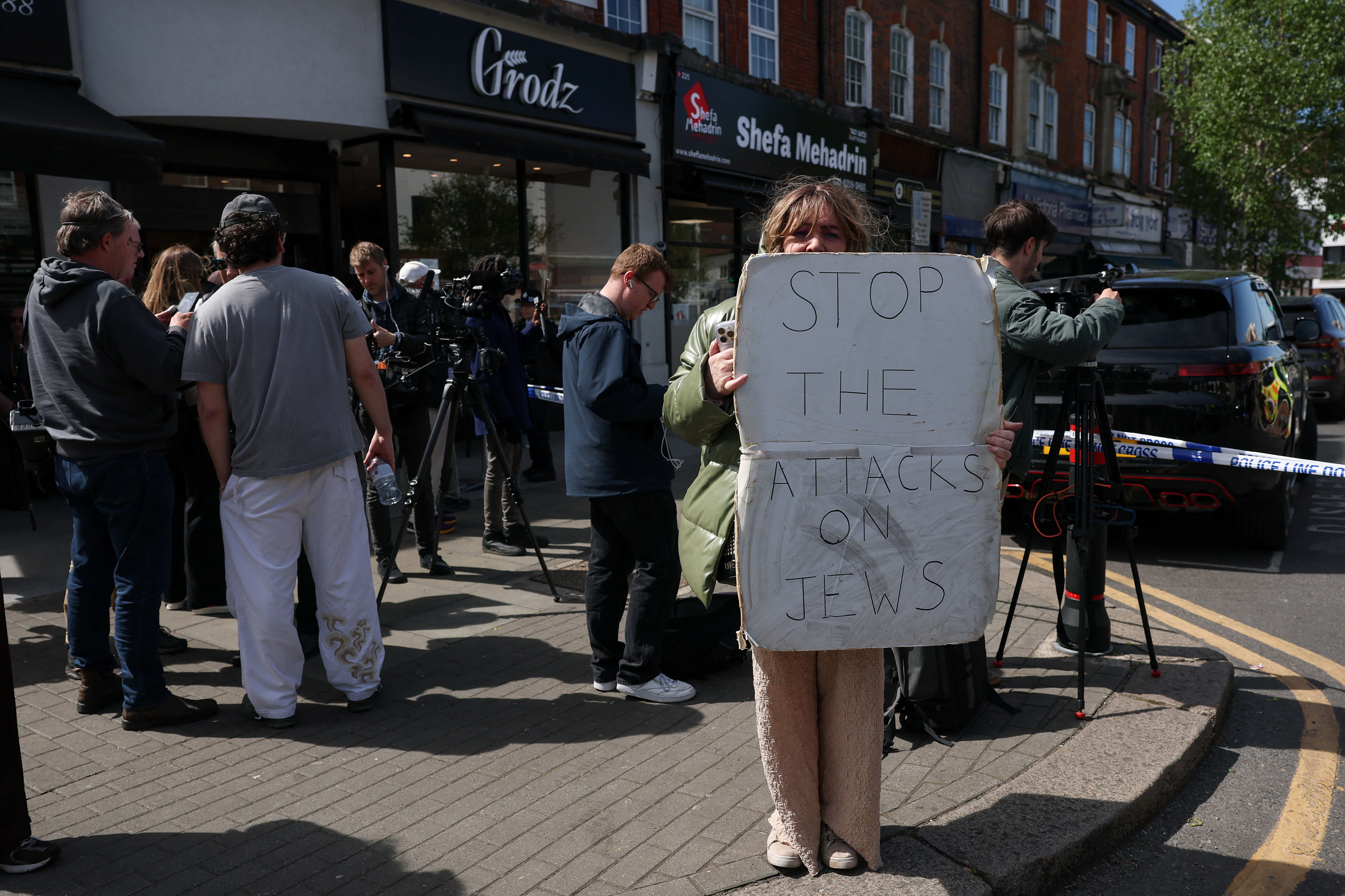 A demonstrator holds a sign near a police cordon, after a man was arrested following a stabbing incident in the Golders Green area, which is home to a large Jewish population, in London, Britain, April 29, 2026. (photo credit: REUTERS/HANNAH MCKAY)