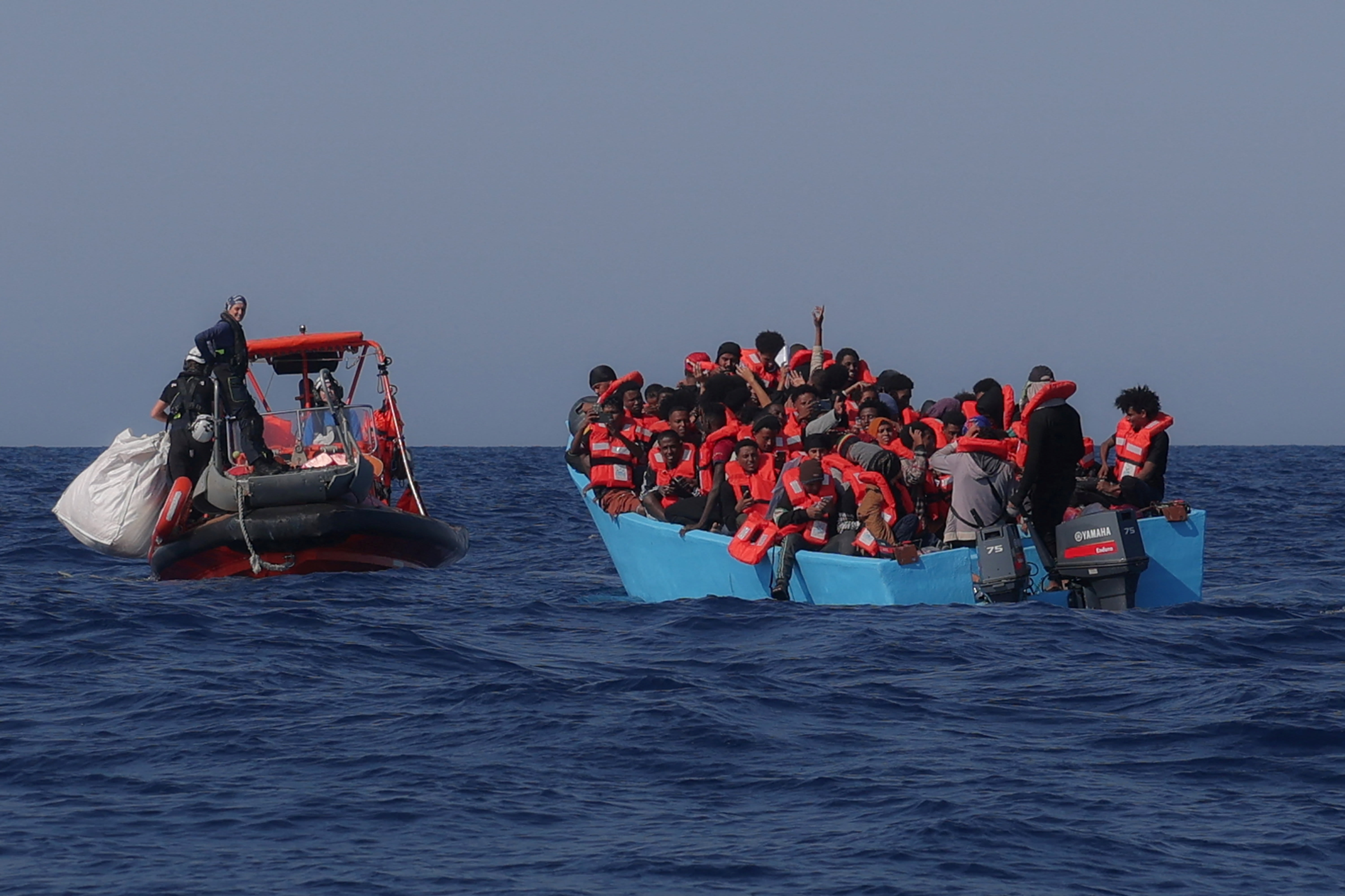 Migrants aboard an overcrowded boat react as they are approached by the crew of the migrant search and rescue ship Sea-Watch 5, operated by the German NGO Sea-Watch, during a rescue operation in the Search and Rescue (SAR) zone in the central Mediterranean, off Libya, August 11, 2025. (photo credit: LOUISA GOULIAMAKI/ REUTERS)