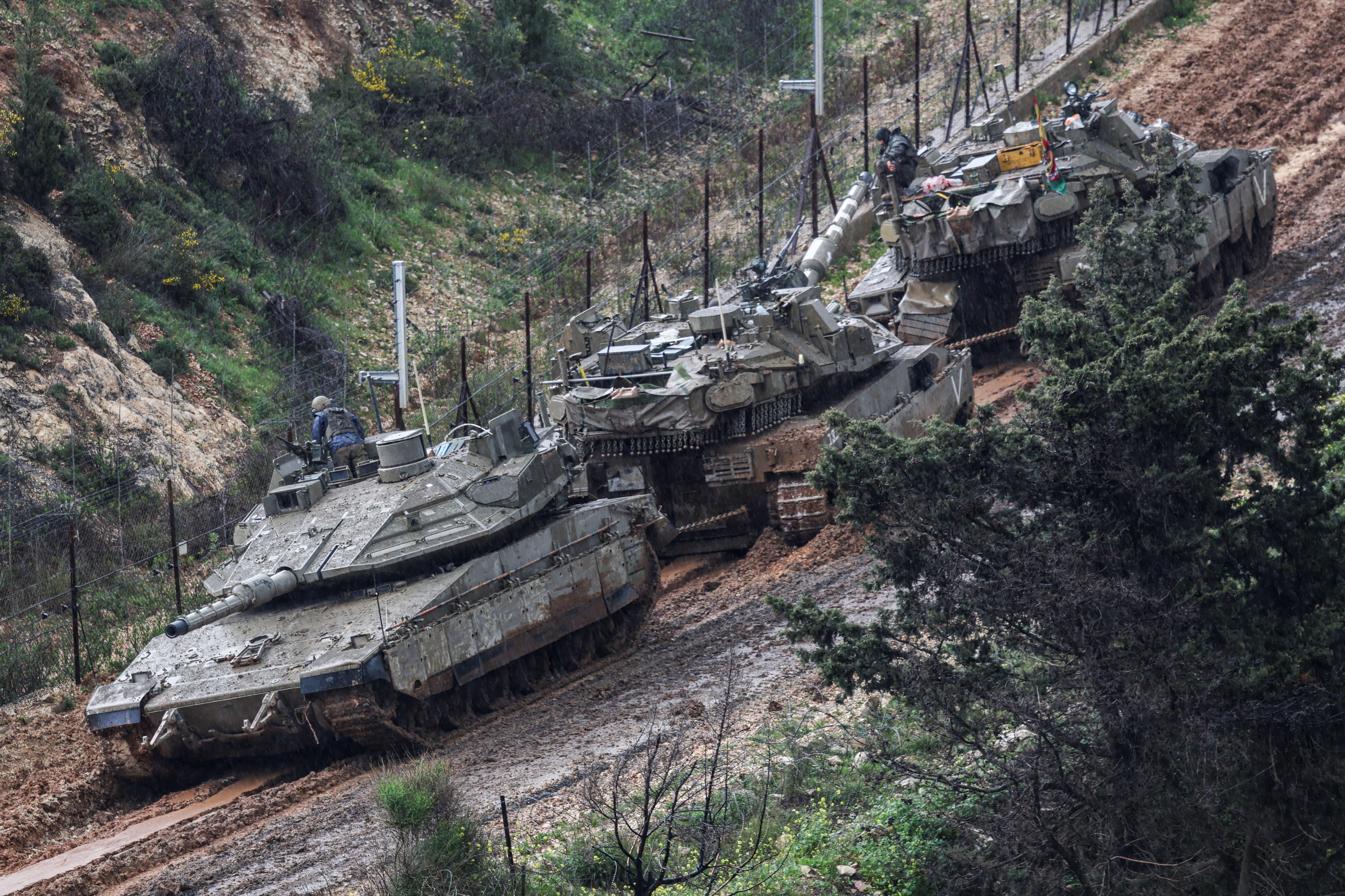 Israeli soldiers lean out from a tank to inspect a disabled tank stuck in the mud, in northern Israel, March 21, 2026 (photo credit: REUTERS/TYRONE SIU)
