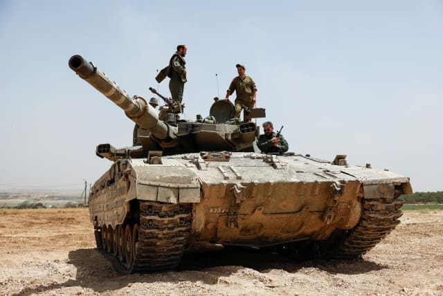  IDF soldiers operate atop a tank near the Gaza border, as seen from Israel, May 21, 2024 (photo credit: REUTERS/AMIR COHEN)