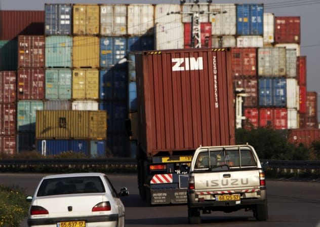 Cars drive behind a truck transporting a Zim container just outside Israel's port of Ashdod February 23, 2012