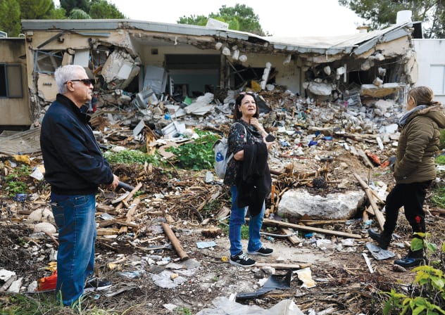  Kibbutz members stand next to a ruined house in Kibbutz Kfar Aza on January 14. 
