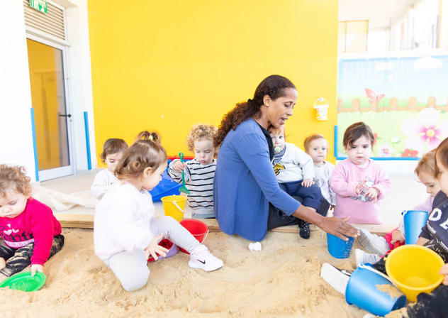 A daycare teacher plays with children at a WIZO daycare center.
