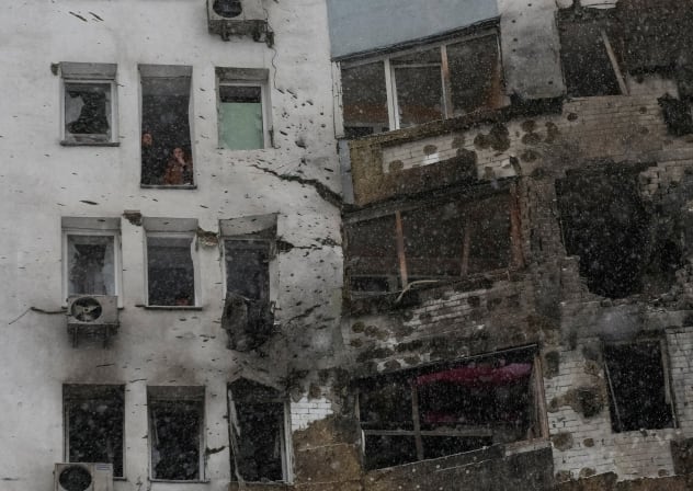 Residents smoke near a broken window of their apartment, damaged during Russian drone strike, amid Russia's attack on Ukraine, in Kyiv, Ukraine January 9, 2026.