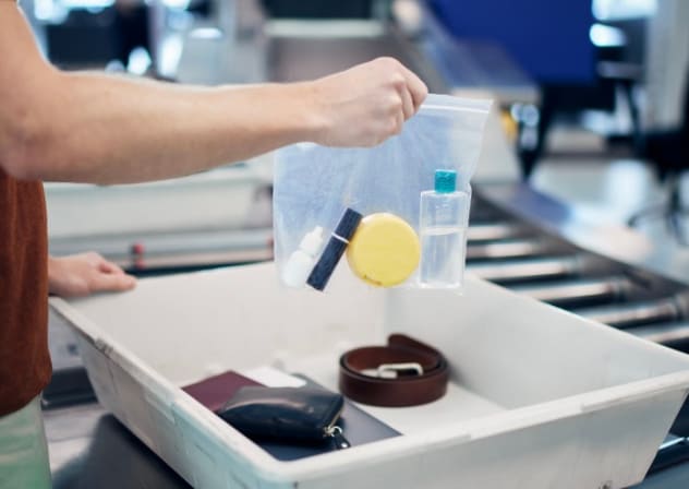 Airport security check before the flight. A passenger holds a plastic bag with liquids.