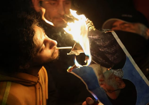 Dos hombres encienden un cigarrillo con una foto en llamas del líder de la República Islámica, Ali Khamenei, mientras la prenden fuego frente a la embajada iraní en Londres, Reino Unido, durante una manifestación celebrada ayer. 