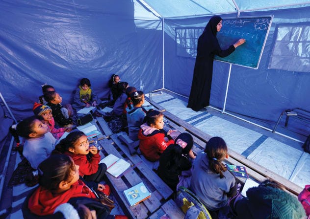 PALESTINIAN CHILDREN study inside a tent in the northern Gaza Strip. Education reform is critical to rebuilding Gaza, the writer says.