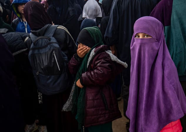 Women and children queue in the rain during a joint security operation by Syria's Kurdish Internal Security Police Force, and the Kurdish-led SDF at Camp Roj where foreign relatives of people suspected of belonging to the Islamic State (IS) group are held, April 5, 2025. 