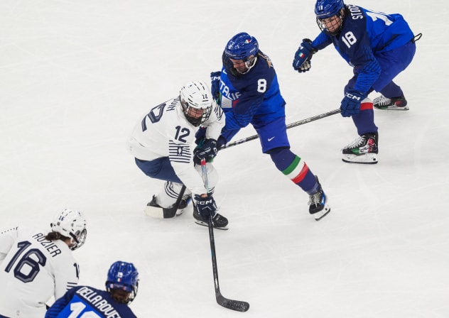 Estelle Duvin (12) of Team France battles for the puck against Anna Caumo (8) of Team Italy during a women's ice hockey Group B game during the Milano Cortina 2026 Olympic Winter Games at Milano Santagiulia Ice Hockey Arena on February 5.