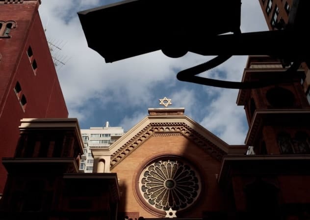 A security camera hangs across the street from the Park East Synagogue, in New York City. Jewish institutions are tightening security amid rising threats.