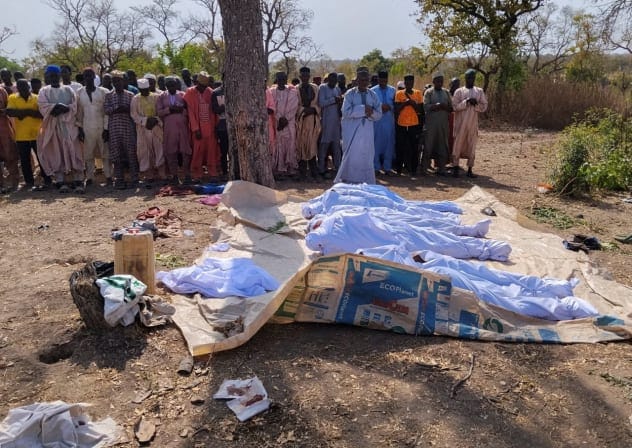 People pray beside the bodies of victims of a terror attack before their burial at Woro community, after an overnight attack by gunmen that killed dozens of residents, in Kaiama Local Government Area of Kwara State, Nigeria, February 4, 2026.