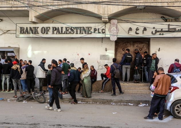 Employees of the Palestinian Authority line up at the ATM outside the Bank of Palestine in Rafah, in the southern Gaza Strip, on December 8, 2023