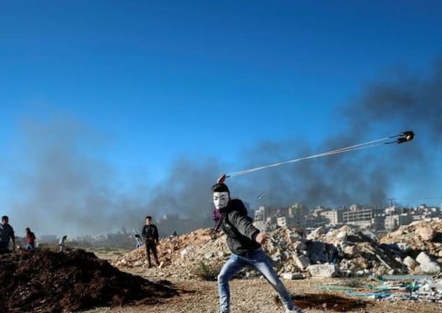 Un palestino lanza piedras con una honda durante los enfrentamientos con las tropas israelíes cerca del asentamiento judío de Beit El, cerca de Ramala, en la Cisjordania ocupada por Israel, el 14 de diciembre de 2018. 