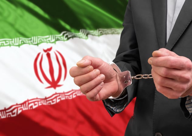 An illustration of a handcuffed individual in a suit, and a backdrop of the Iranian flag.