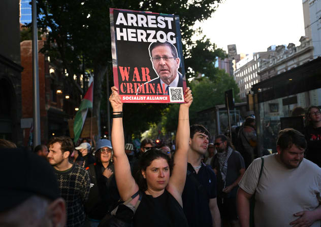 A protester holds aloft a placard as they march during the visit of Israel's President Isaac Herzog in Melbourne on February 12, 2026