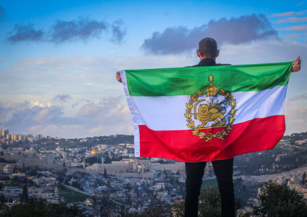 Alex Winston stands overlooking Jerusalem with an Iranian Lion and Sun flag on February 13, 2026. 