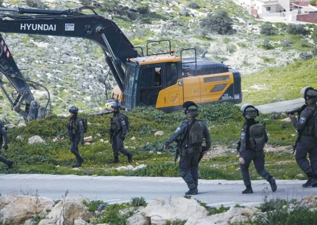 Las fuerzas de seguridad israelíes vigilan mientras unas excavadoras derriban un edificio palestino en Cisjordania, el miércoles. 
