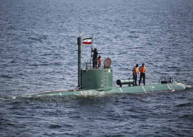 Military personnel place a flag on a submarine during the Velayat-90 war games by the Iranian navy in the Strait of Hormuz in southern Iran December 27, 2011