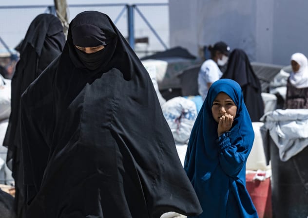 A woman and child walk in the the al-Hol camp in Syria's northeastern Al-Hasakah Governorate on July 28, 2024, as Syrian families of suspected Islamic State fighters prepare to return to their homes in the countryside of Deir Ezzor.