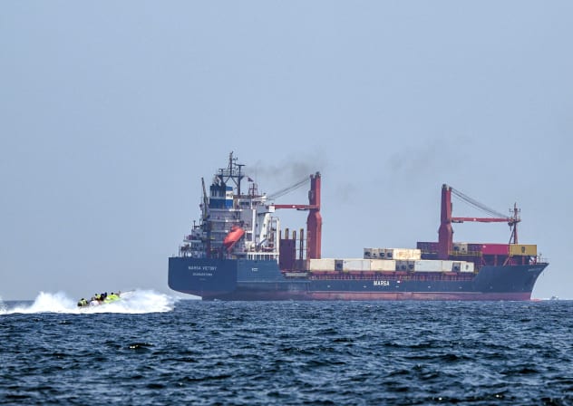  A boat approaches the St Kitt's and Nevis-flagged container ship Marsa Victory while crusing in the waters of the Strait of Hormuz off the coast of Khasab in Oman's northern Musandam peninsula on June 25, 2025.