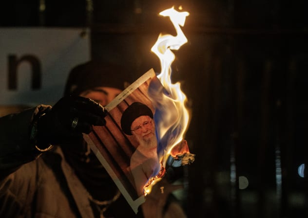  A protester burns an image of Ali Khamenei, Supreme Leader of Iran during a protest outside the Iranian Embassy on January 14, 2026 in London, England.