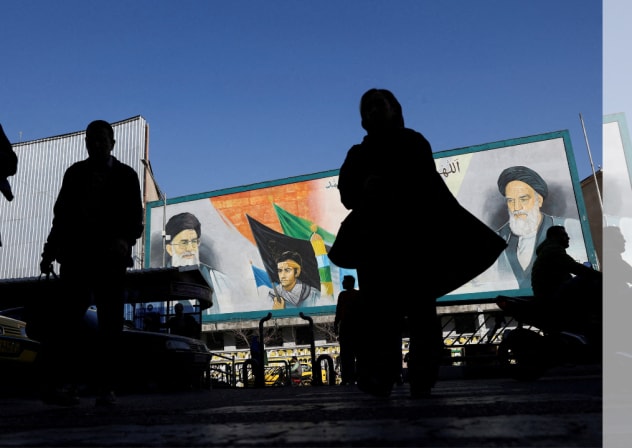People walk near a mural featuring images of Iran's Supreme Leader Ayatollah Ali Khamenei and leader of Iran's 1979 Islamic Revolution Ayatollah Ruhollah Khomeini, on a street in Tehran, Iran, February 17, 2026.