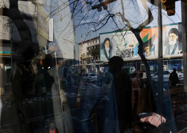 A sign with a depiction Ali Khamenei, is reflected in a shop window in Tehran, February 19, 2026. 