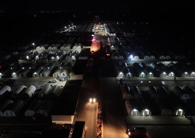This aerial view shows vehicles by the tent shelters for people arriving from the Hol camp in eastern Syria, at the Akbaran camp near Akhtarin, in the north of Aleppo province, on February 17, 2026. 