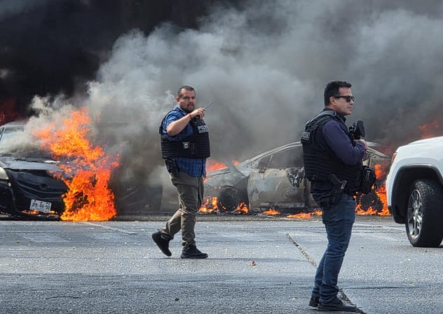 Police officers secure the area where vehicles were set on fire by organized crime members to block a road following a military operation in which a government source said Mexican drug lord Nemesio Oseguera, commonly known as "El Mencho," was killed, in Zapopan, Mexico, February 22, 2026.