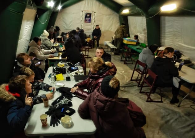 People charge their devices, eat and warm themselves at a mobile resilience hub set up in a residential district amid electricity and heating interruptions on Jan. 20, 2026 in Kyiv, Ukraine. 