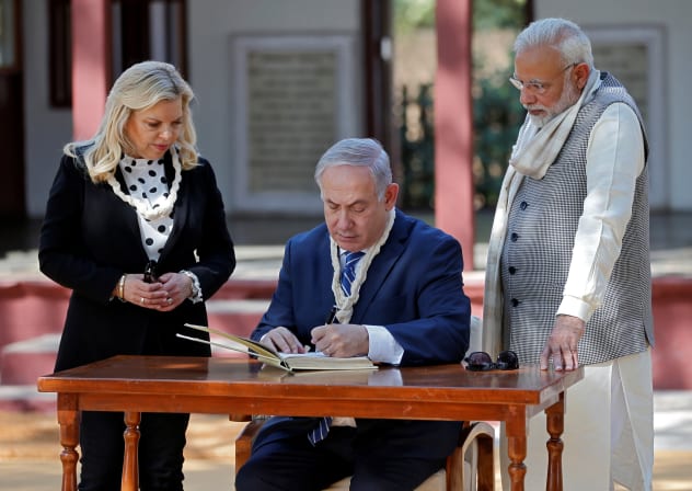 Israeli Prime Minister Benjamin Netanyahu writes a message in the visitor's book as his wife Sara and his Indian counterpart Narendra Modi look on during their visit to Gandhi Ashram in Ahmedabad, India, January 17, 2018.