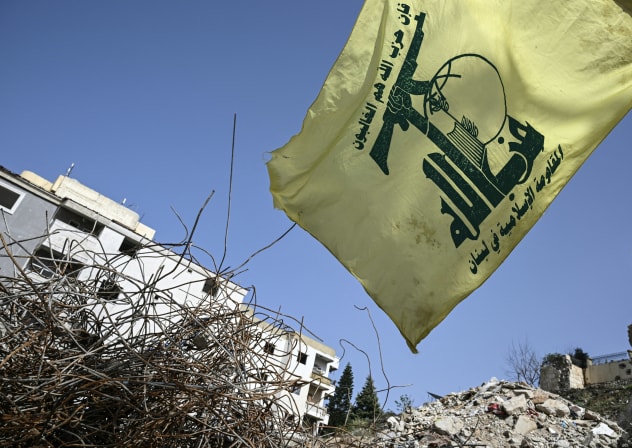 A flag of the Lebanese Shiite movement Hezbollah flutters above the rubble of a building that was hit in January by an Israeli strike in the southern Lebanese village of Qannarit, on February 16, 2026.