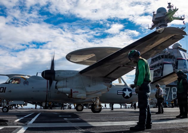 US Navy sailors observe as an E-2D Hawkeye aircraft approaches an aircraft catapult to launch on the flight deck of the aircraft carrier, USS Gerald R. Ford, while operating in support of the Operation Epic Fury attack on Iran from an undisclosed location March 1, 2026.
