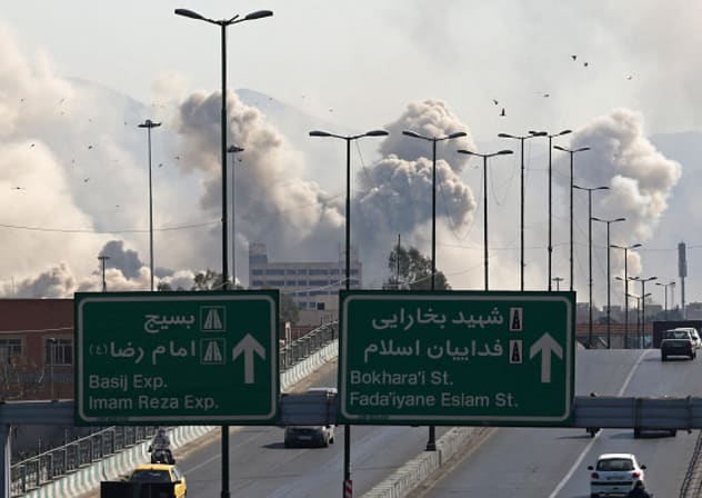 Motorists drive along an expressway as plumes of smoke rise after a strike in Tehran on March 5, 2026.
