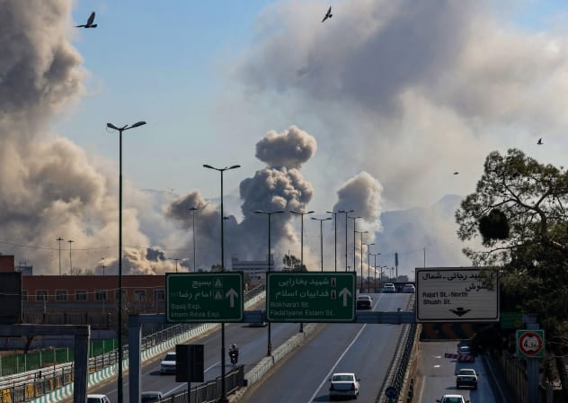 Motorists drive along an expressway as plumes of smoke rise after a strike in Tehran on March 5, 2026.