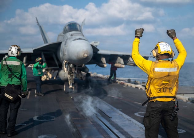 A US Navy sailor signals an F/A-18E Super Hornet on the flight deck of the Nimitz-class aircraft carrier USS Abraham Lincoln in support of the Operation Epic Fury attack on Iran at an undisclosed location March 4, 2026. 