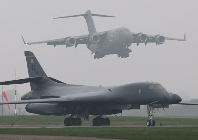 A United States Air Force (USAF) Boeing C-17A Globemaster comes in to land behind a USAF B-1B bomber parked beside the runway at RAF Fairford airbase, in Fairford, Britain, March 8, 2026.