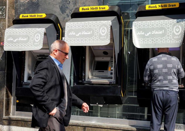 A man walks past another using an ATM machine of Iran's Melli Bank in Tehran on February 21, 2026; illustrative.