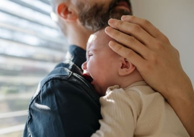 A father holding a crying baby
