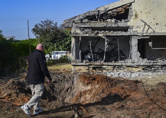 People stand at the scene where a house was hit by a Hezbollah missile fired toward central Israel, March 12, 2026