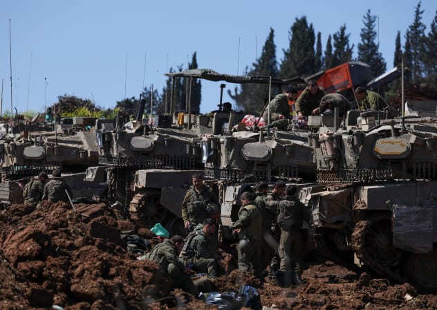 Israeli soldiers gather next to tanks on the Israeli side of the border with Lebanon, in northern Israel, March 17, 2026