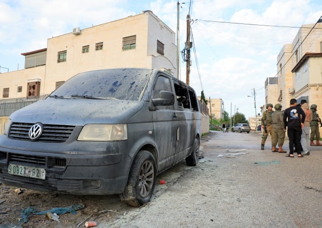 ISRAELI SOLDIERS stand near a vehicle, which Palestinians say was burned by Israeli settlers, in Hebron in the West Bank, March 19, 2026.