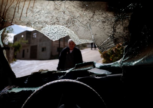 A man looks at a damaged vehicle, which Palestinians say was burned by Israeli settlers last night, in Al-Fandaqumiya, near Jenin, in the West Bank, March 22, 2026.