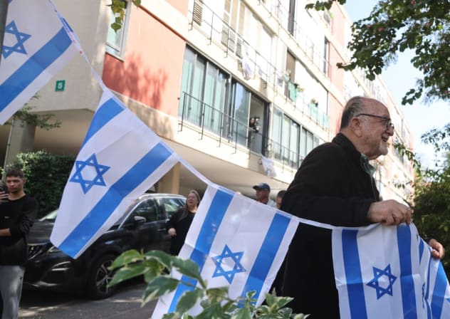 Un hombre ondea banderas israelíes tras un ataque iraní en Givatayim, en el centro de Israel, el 6 de marzo de 2026. 